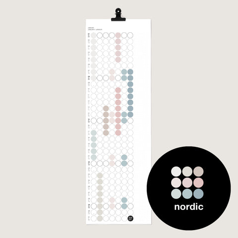 dot on weißer Monatsplaner Wandkalender mit Klebepunkten im Format 23x72 cm beklebt mit Klebepunkten in den nordischen Tönen rose, beige, hellblau und schwarzer Metallklammer