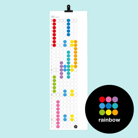 dot on weißer Monatsplaner Wandkalender mit Klebepunkten im Format 23x72 cm beklebt mit Klebepunkten in Regenbogen Farben gelb, rot, grün, lila, türkis, orange, blau und schwarzer Metallklammer